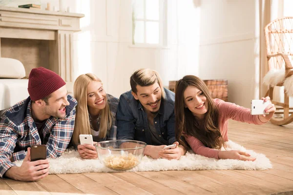 Happy young friends lying on carpet — Stock Photo, Image