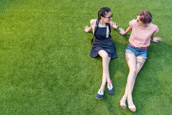 Meninas multiétnicas descansando na grama — Fotografia de Stock