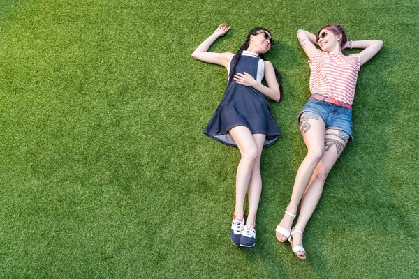 Multiethnic girls lying on grass — Stock Photo, Image