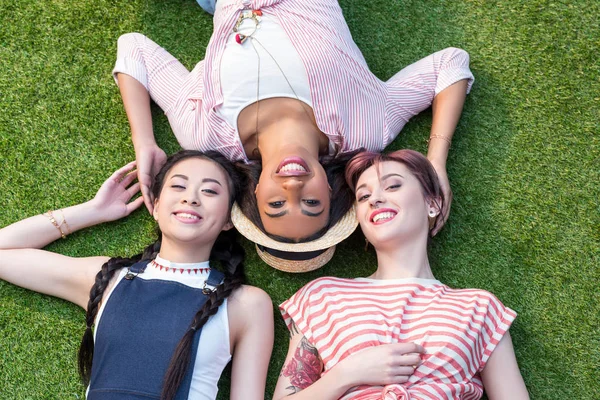 Meninas multiétnicas deitado na grama — Fotografia de Stock