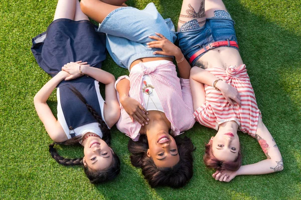 Meninas multiétnicas deitado na grama — Fotografia de Stock