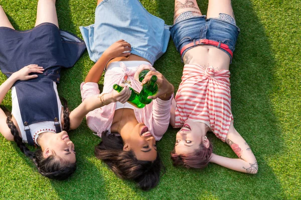 Meninas multiétnicas beber cerveja na grama — Fotografia de Stock