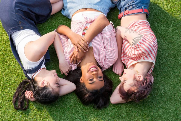 Багатоетнічні дівчата лежать на траві — стокове фото