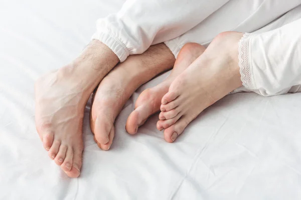 Feet of couple lying in bed — Free Stock Photo