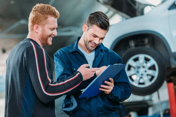 Automechanic showing client clipboard — Stock Photo, Image