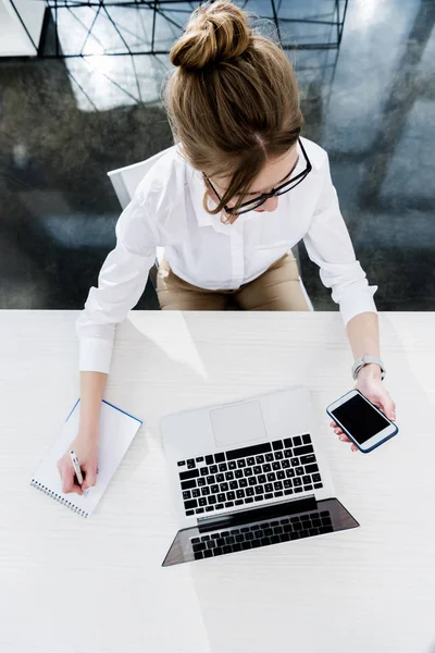 Деловая женщина, работающая с ноутбуком и смартфоном — стоковое фото