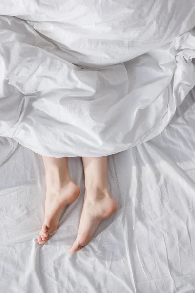 Γυναικεία πόδια εκτείνονται από κουβέρτα — Φωτογραφία Αρχείου