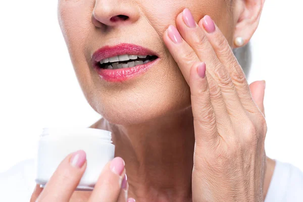 Mujer mayor aplicando crema facial —  Fotos de Stock