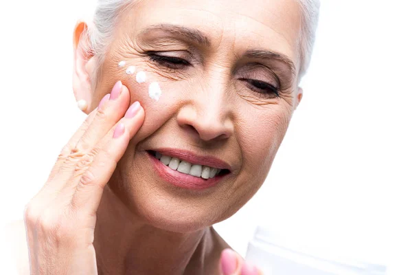 Mujer mayor aplicando crema — Foto de Stock