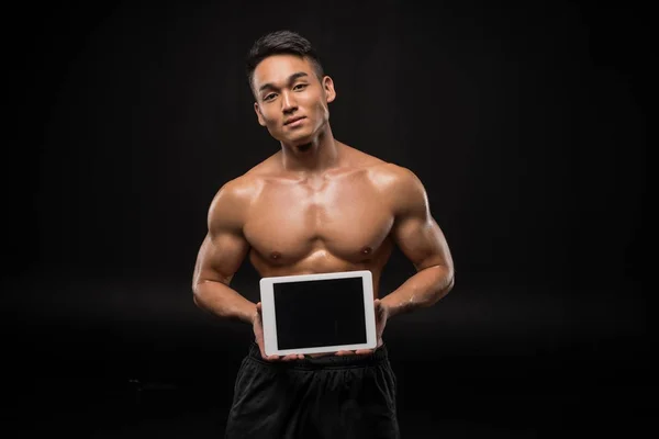Мускулистый человек с цифровым планшетом — стоковое фото