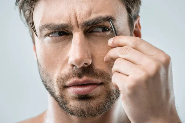 Чоловік вириває брови пінцетом — стокове фото
