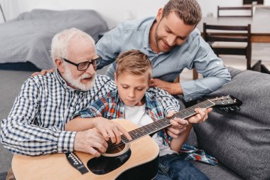 Grandpa teaching boy play guitar clipart