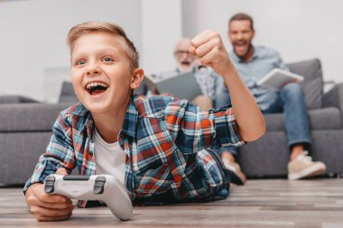 Cheering boy playing videogames with gamepad clipart