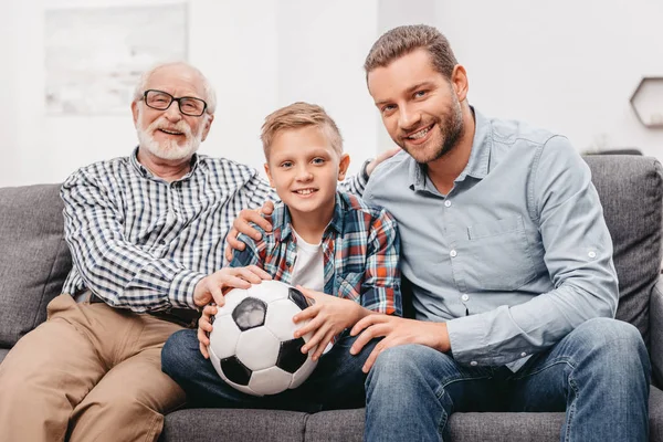 Família sentada no sofá com bola de futebol — Fotografia de Stock