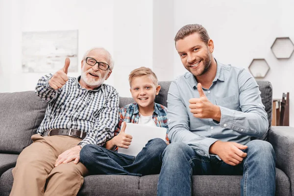 Familj på soffan visar tummen — Stockfoto
