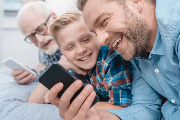 Happy family with smartphone on bed — Stock Photo, Image