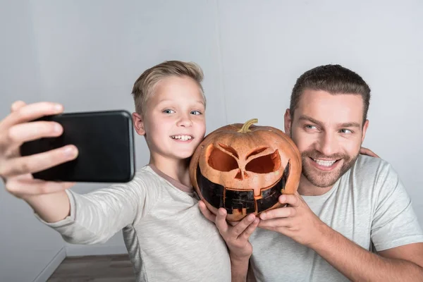 Vader en zoon met halloween pompoen — Stockfoto