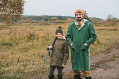 Father and son with gun posing to camera clipart