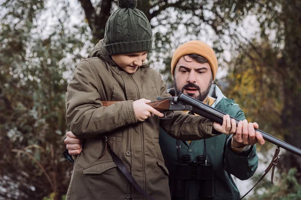Отец показывает сыну, как заряжать пистолет. — стоковое фото