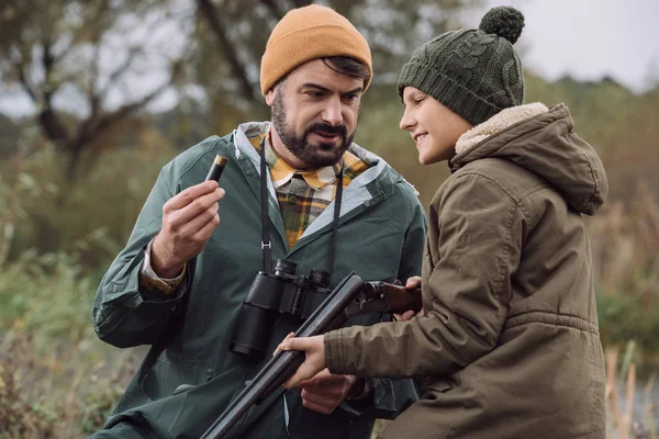 Father showing how to load bullet in gun — Stock Photo, Image