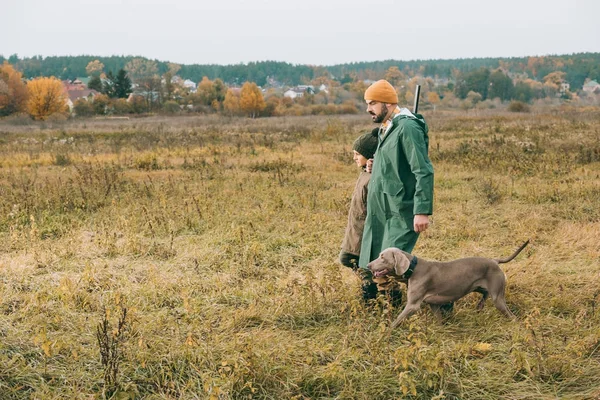 Apa és fia, gyaloglás a kutya mezőbe — Stock Fotó