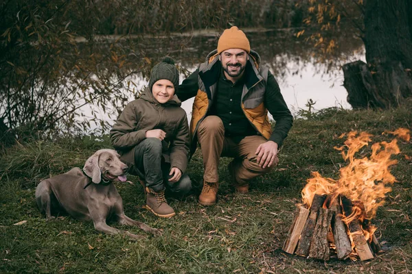 Far og sønn sitter ved bålet – stockfoto