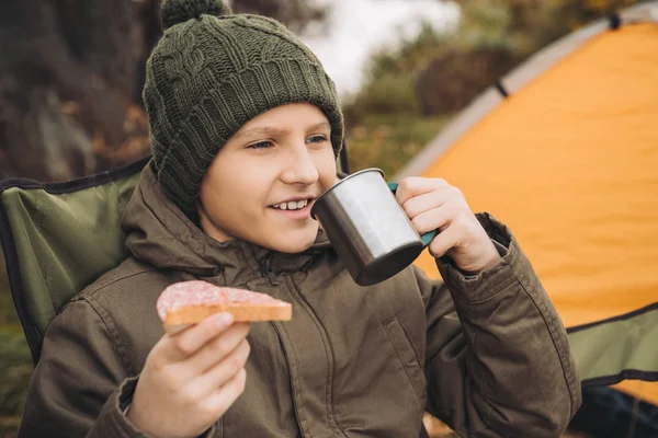 Мальчик пьет чай и ест сэндвич — стоковое фото