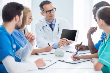 doctors having conversation and looking at tablet clipart