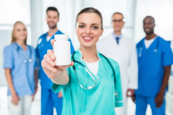 Медсестра показывает банку с таблетками — стоковое фото