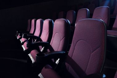 red seats in empty dark movie theater clipart