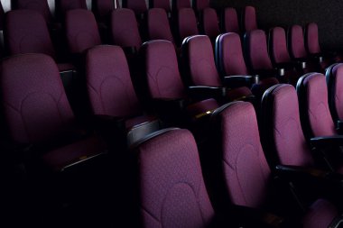 red seats in empty dark movie theater clipart