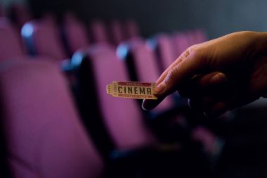 cropped view of person holding cinema ticket in hand clipart
