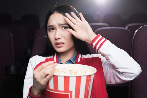 受惊吓的亚洲女孩吃爆米花和看电影在电影院 — 图库照片