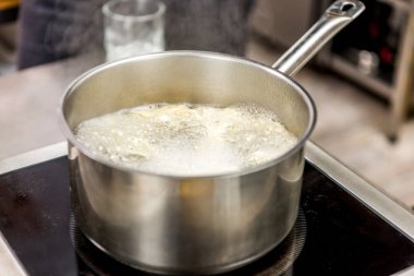 pasta in boiling water in pot on electric stove clipart