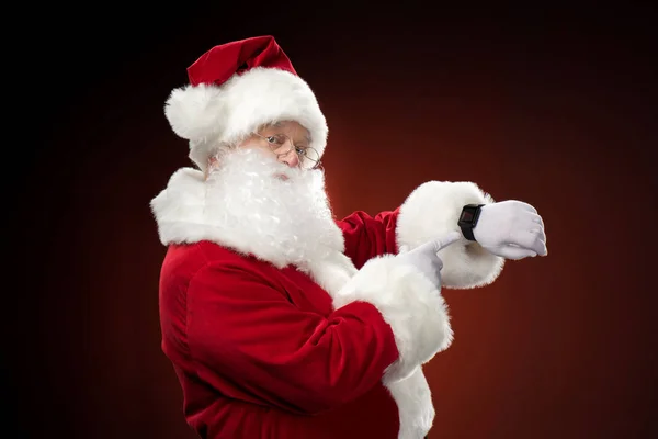 Papai Noel apontando no relógio inteligente — Fotografia de Stock