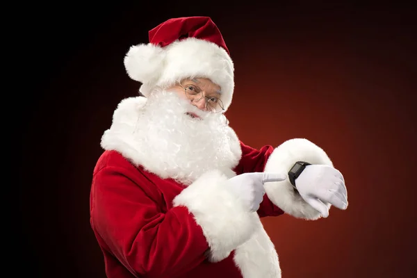 Papá Noel señalando el reloj inteligente - foto de stock