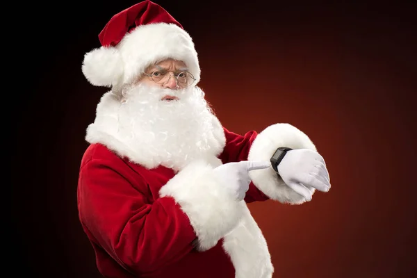 Papá Noel señalando el reloj inteligente - foto de stock