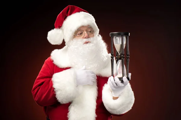 Papai Noel olhando para ampulheta — Fotografia de Stock