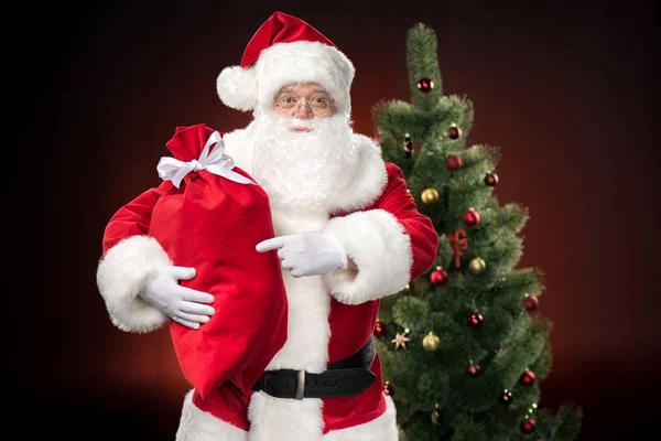 Santa Claus pointing at sack — Stock Photo