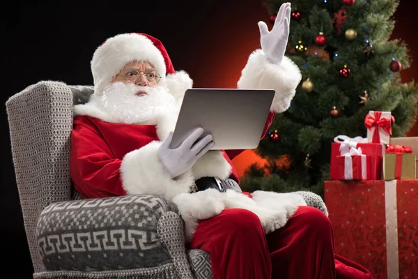Santa Claus usando el ordenador portátil y el gesto - foto de stock