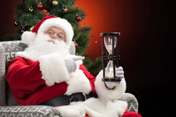 Santa Claus apuntando al reloj de arena - foto de stock