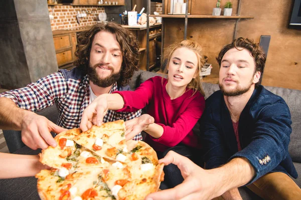 Amici sorridenti che assaggiano pizza — Foto stock