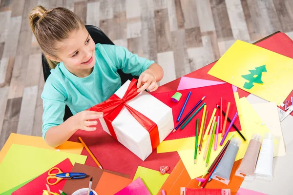 Schoolchild wrapping gift box — Stock Photo