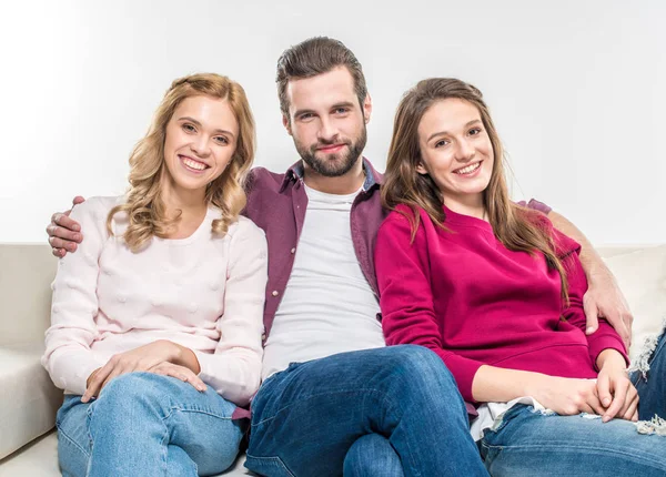 Smiling friends embracing on couch — Stock Photo