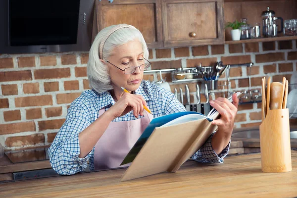 Senior woman with cookbook — Stock Photo