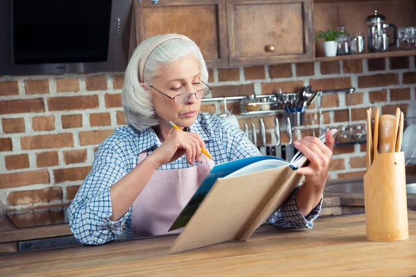 Mulher sênior com livro de receitas — Fotografia de Stock