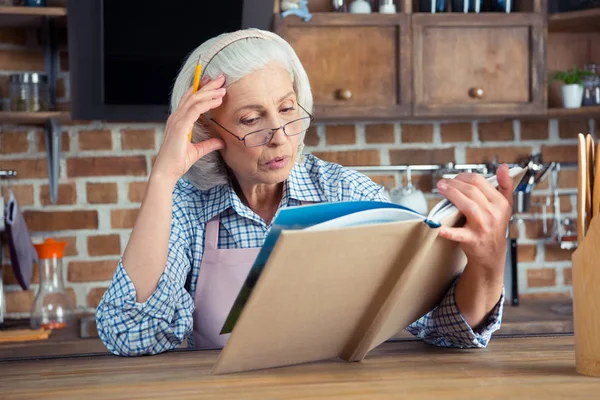 Mulher sênior com livro de receitas — Fotografia de Stock