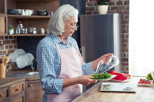 Woman unfolded greenery in kitchen — Stock Photo