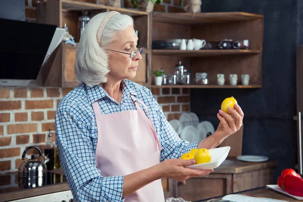 Женщина смотрит на лимоны на кухне — стоковое фото