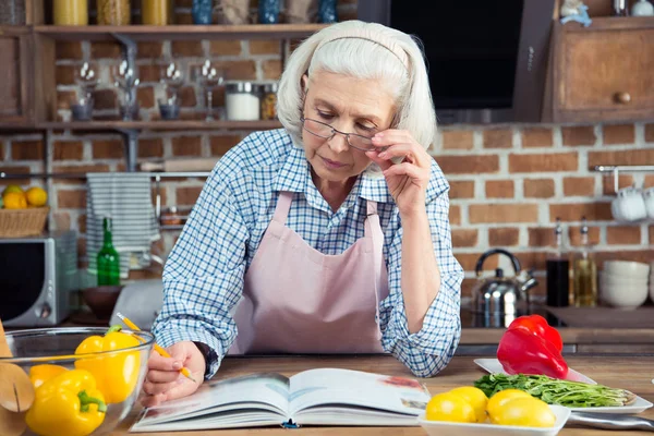 Mulher sênior com livro de receitas — Fotografia de Stock